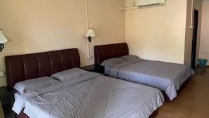 Una habitación con dos camas, piso de madera, ventilador de techo y aire acondicionado instalado en la pared.