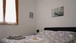 A bedroom with a bed, a window, a painting, and a nightstand. - Casa Marisa, Salento by design. Within walking distance of the pearls of Salento! (Torre Saracena)
