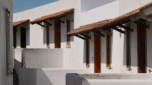 A courtyard with white buildings, tiled flooring, and wooden doors. - Casa Marisa, Salento by design. Within walking distance of the pearls of Salento! (Torre Saracena)