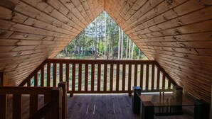 A wooden attic bedroom with a triangular ceiling, a wooden deck, and a view of a forest. - Amazing home in Ostrowite with sauna (Ostrowite)