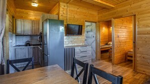 A compact wooden cabin with a kitchen area, a dining table, and a sleeping area. - Amazing home in Ostrowite with sauna (Ostrowite)
