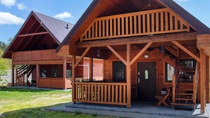 A two-story wooden cabin with a covered porch, a staircase, and a door with a window. - Amazing home in Ostrowite with sauna (Ostrowite)