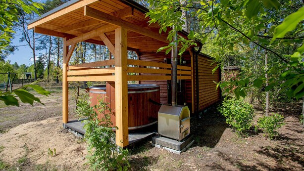 Une cabane en bois dotée d’un porche couvert et d’un poêle à bois.