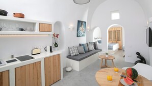 Une cuisine moderne avec des meubles blancs, un four encastré et un coin repas comprenant une table ronde et des chaises.