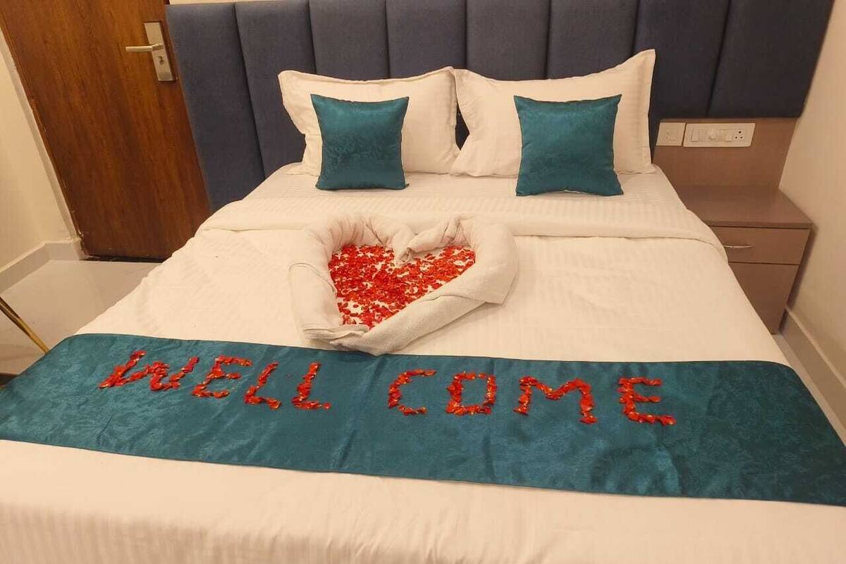 Una cama bien hecha con una decoración en forma de corazón y un cartel que dice "WELCOME" sobre la colcha.