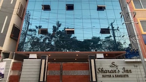 A hotel with a modern facade, multiple windows, and a sign indicating it offers suites and banquets. - SHARAN'S INN SUTES & BANQUETS (Hyderabad)