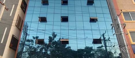 Un hotel con fachada moderna, varias ventanas y un letrero que indica que ofrece suites y salones de banquetes.