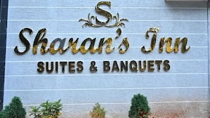A sign for Sharan's Inn Suites & Banquets with a rustic wooden background and decorative gold lettering. - SHARAN'S INN SUTES & BANQUETS (Hyderabad)