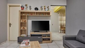 A modern living room with a flat-screen TV, wooden entertainment unit, and a grey sofa.