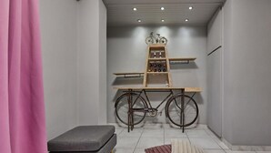 A bathroom with a grey bench, a wooden ladder shelf, and a bicycle.