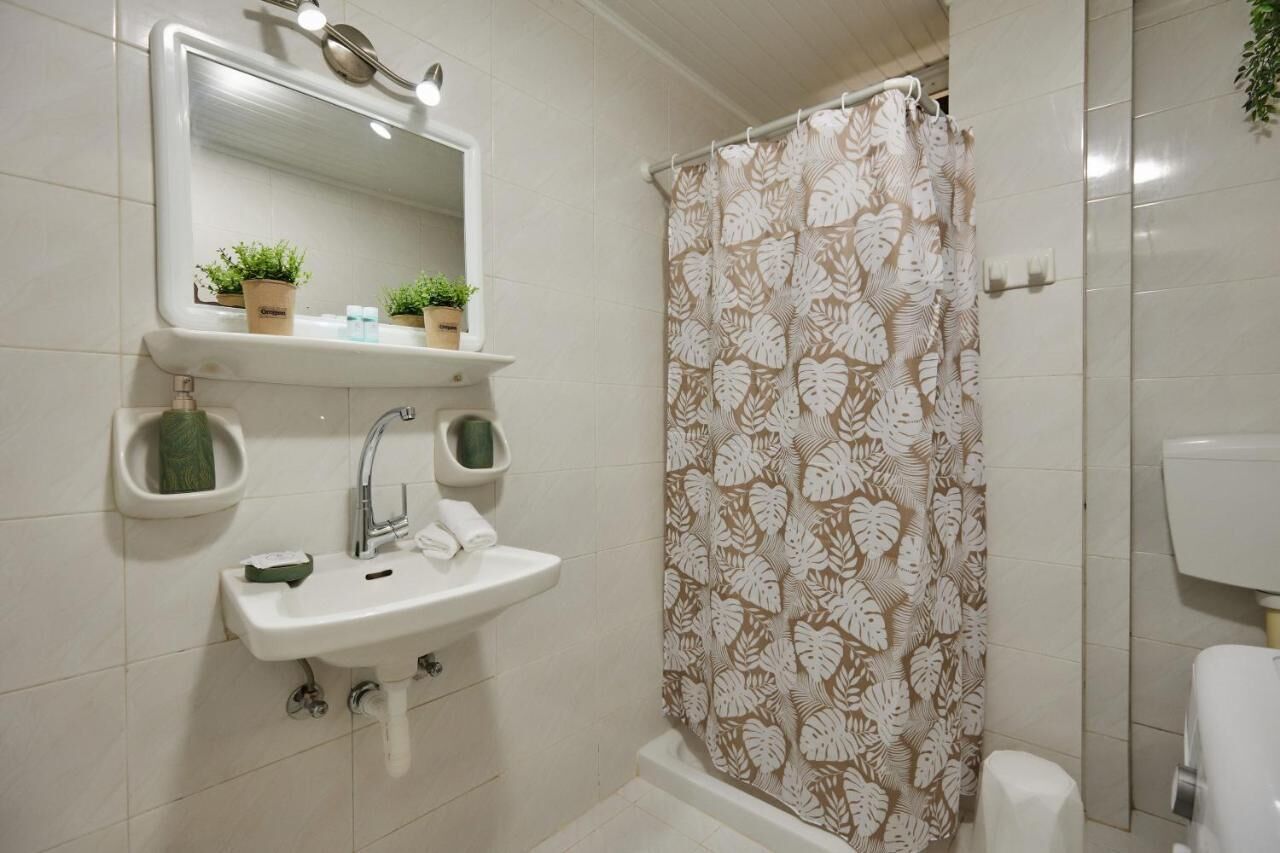 A bathroom with a sink, mirror, and shower curtain.