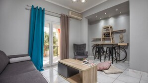 A modern living room with a sofa, a coffee table, and a dining area with a ladder and stools.