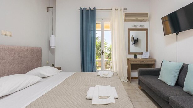A hotel room with a bed, a sofa, a desk, and a TV.