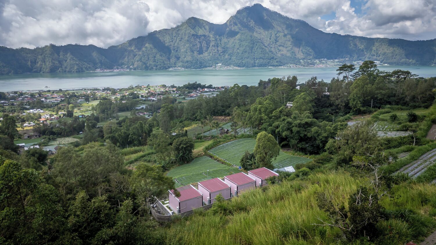 Une ville côtière offrant une vue sur la mer et les montagnes. On peut y apercevoir des maisons et des champs.
