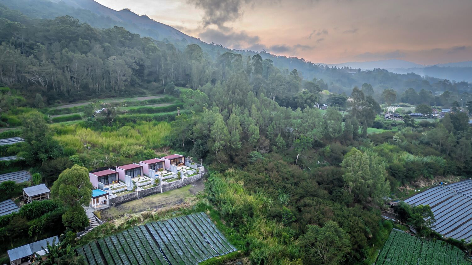 Una casa moderna con un jardín amplio, rodeada de abundante vegetación y colinas.
