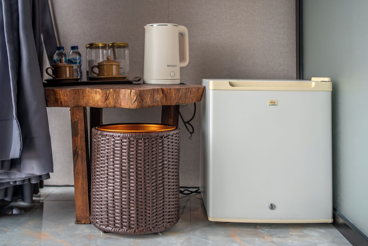 Una kitchenette compacta con una cafetera blanca, un refrigerador pequeño y una cesta de mimbre.