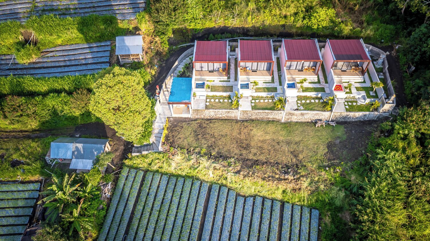 An aerial view of a resort with multiple buildings, a swimming pool, and surrounding greenery.