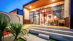 Una casa moderna con fachada de madera, amplios ventanales de vidrio y un interior bien iluminado.