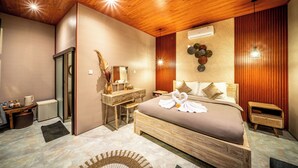 Una habitación de hotel moderna con techo de madera, una cama grande con una toalla con forma de corazón, una tocador con espejo y un aire acondicionado de pared.