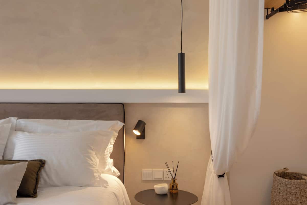 Un dormitorio moderno con una cama grande, una mesita de noche y una pequeña mesa redonda con una vela.