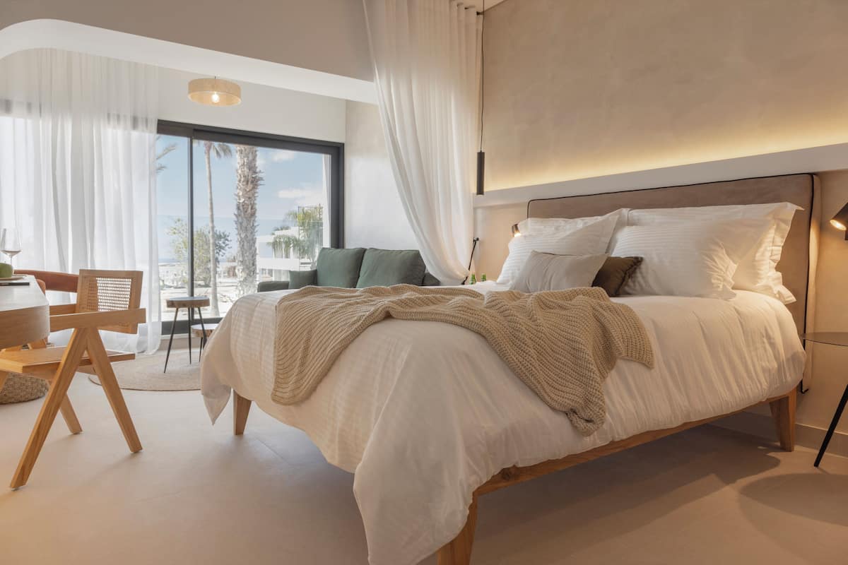 Un dormitorio moderno con una cama grande, un escritorio y vistas a palmeras.
