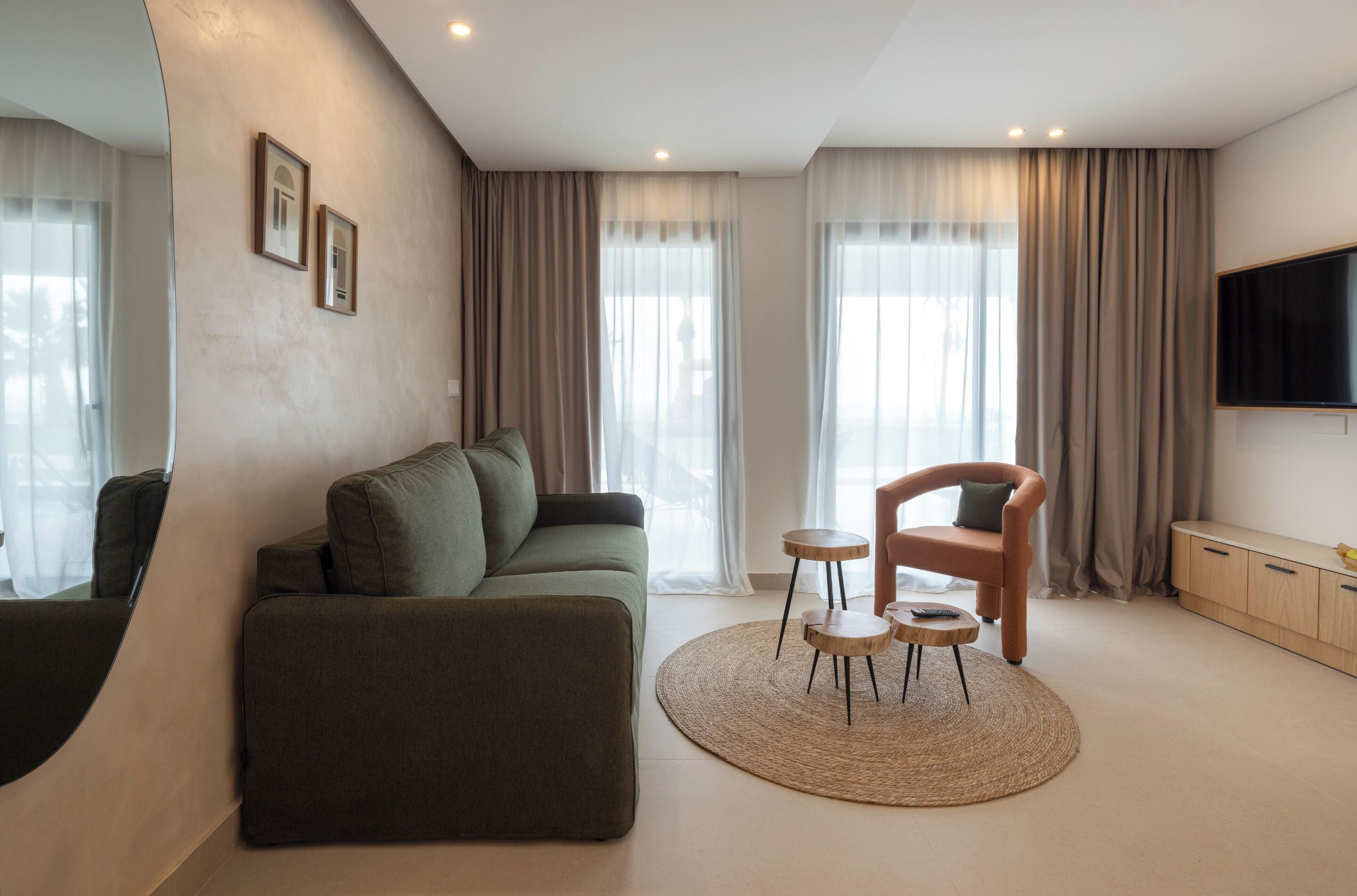 A modern living room with a sofa, a chair, a small table, and a TV mounted on the wall.
