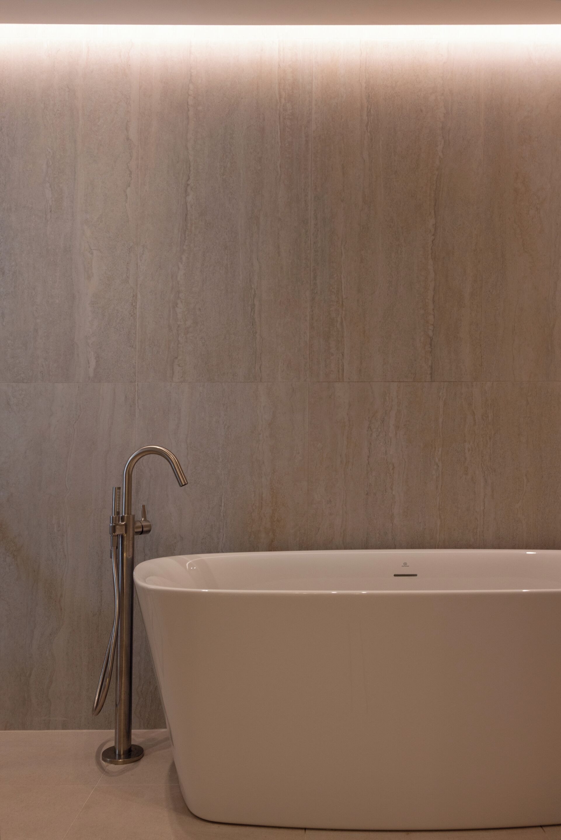 A modern bathroom with a freestanding bathtub, a handheld showerhead, and a wall-mounted faucet.