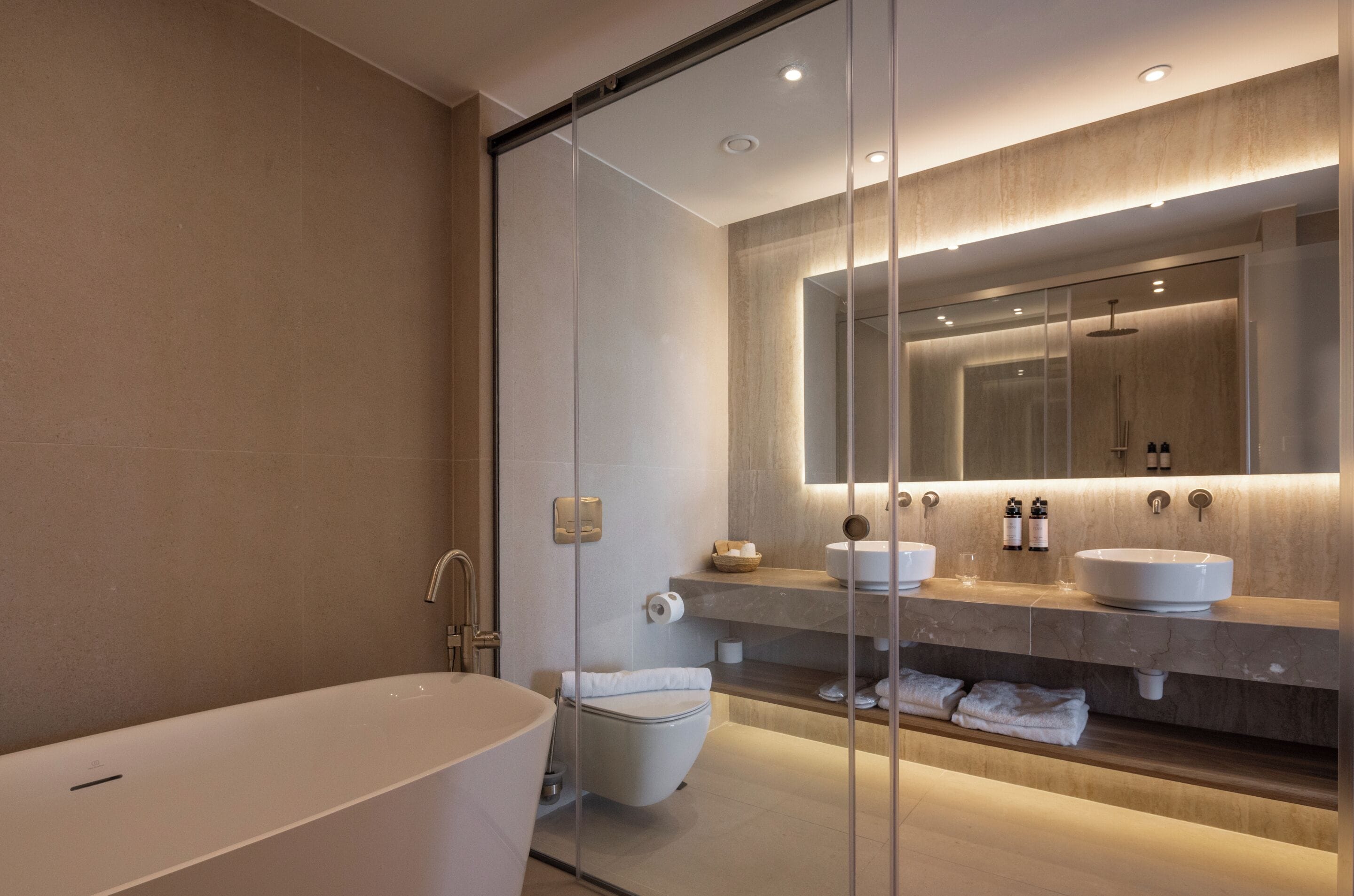 A modern bathroom with a freestanding bathtub, a toilet, and a vanity with a large mirror.