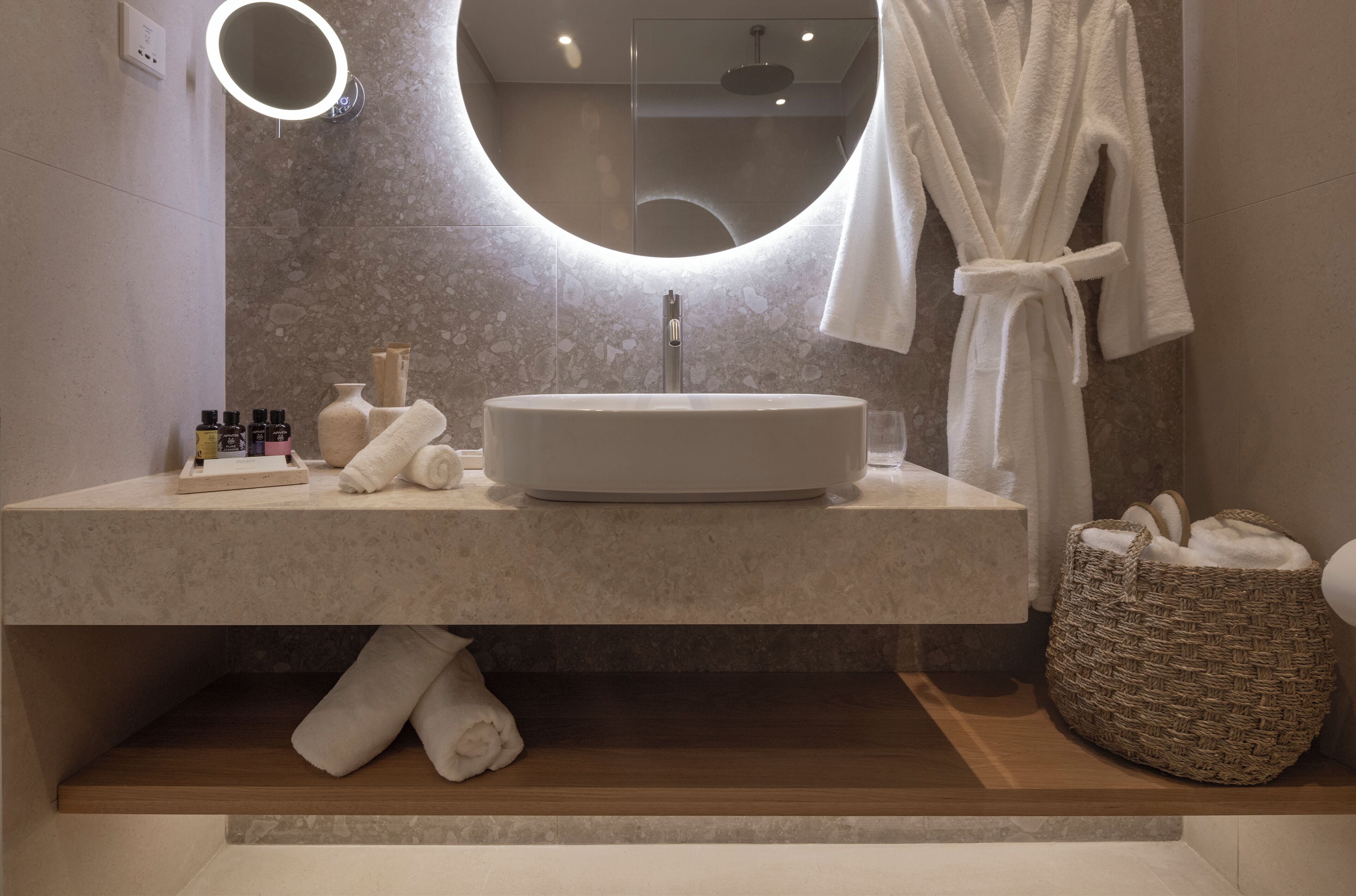 A modern bathroom with a round mirror, a large sink, and a towel rack.