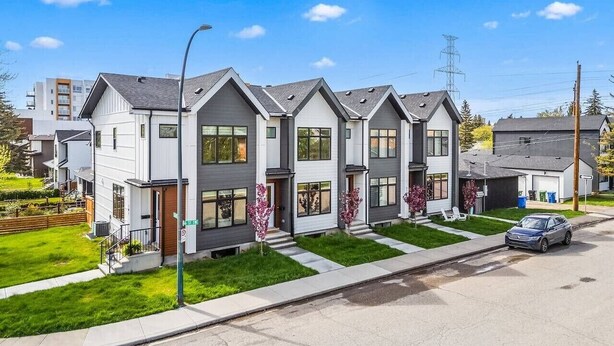 A row of modern two-story houses with a well-maintained lawn and a clear sky.