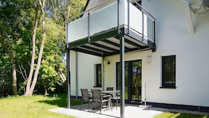 A modern house with a covered patio area featuring a table and chairs.