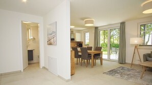 A spacious living area with a dining table and chairs, a sofa, and a lamp.
