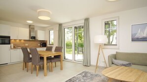 A modern living room with a dining area, a sofa, a coffee table, and a lamp.