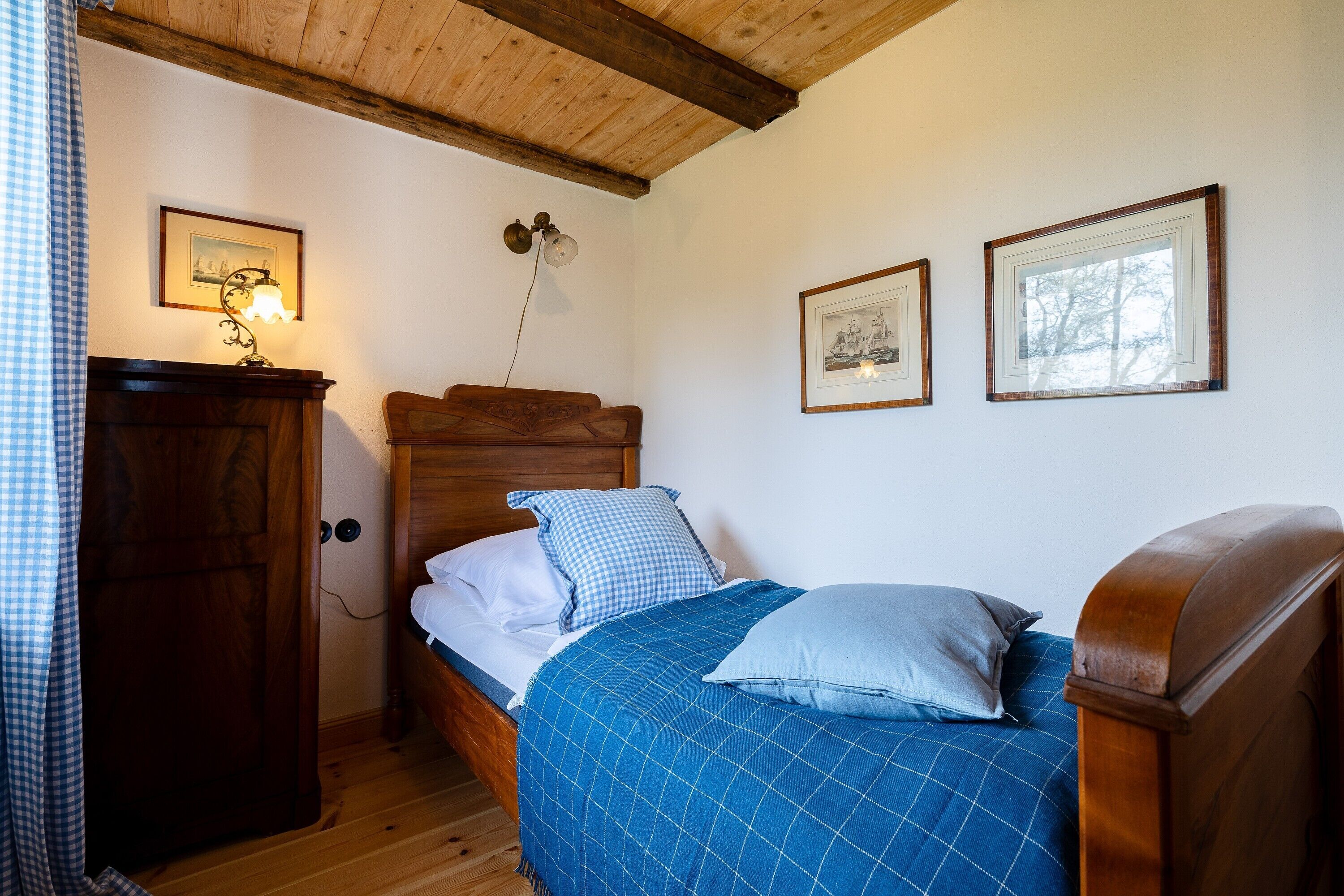 Una camera da letto con un letto di legno, un armadio in legno e due quadri appesi al muro.