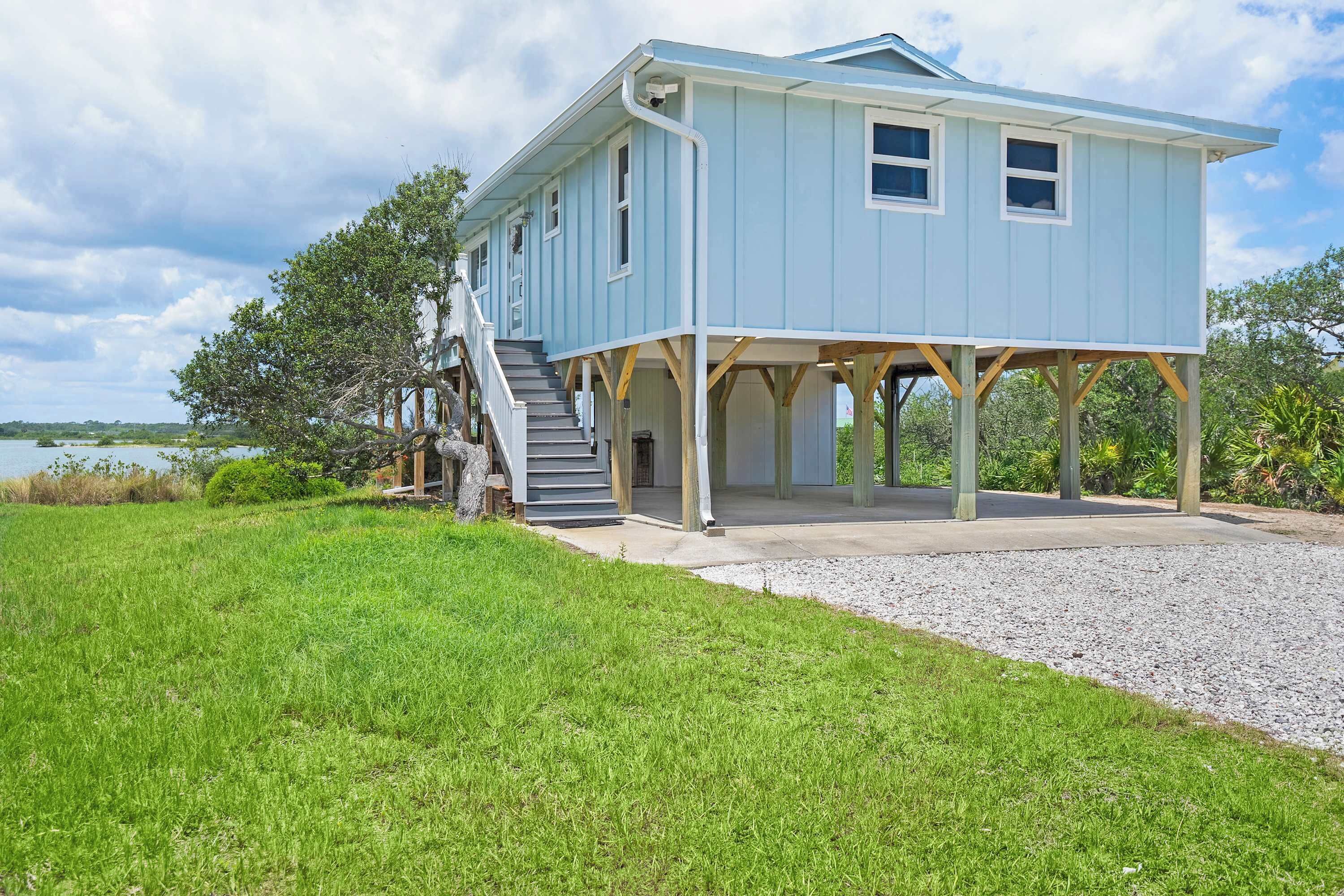 A light blue house with a covered porch and a staircase leading to the entrance.