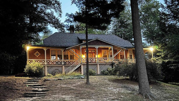 A lodge with a covered porch, stone steps, and a stone wall. - Forest Lodge Serenity on Long Lake - Dogs Welcome! (Traverse City)