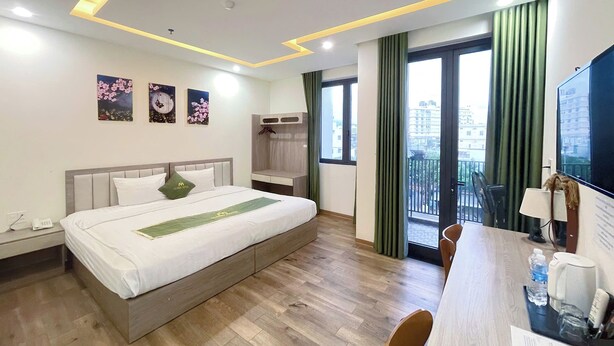 Ein Hotelzimmer mit Bett, Schreibtisch, Stuhl, Fernseher und einem Balkon mit Blick.