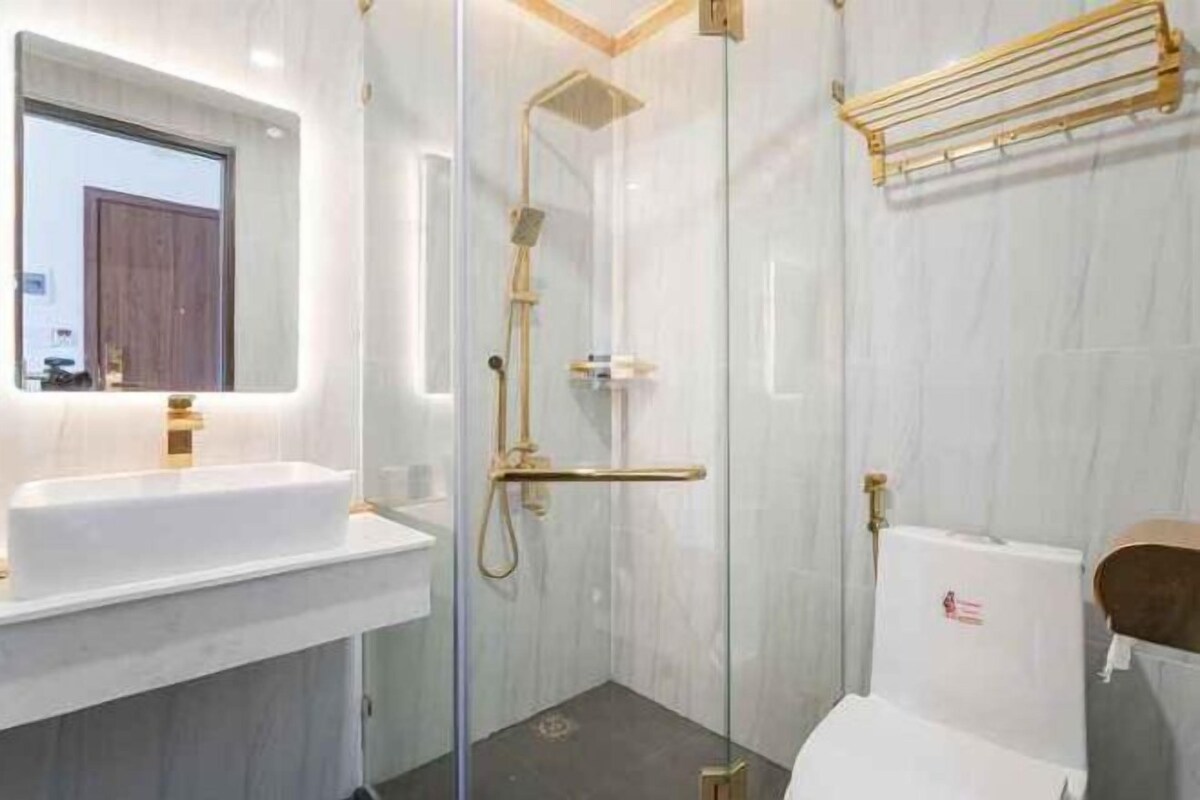 Un baño moderno con ducha envuelta en vidrio, un lavamanos blanco y un inodoro.