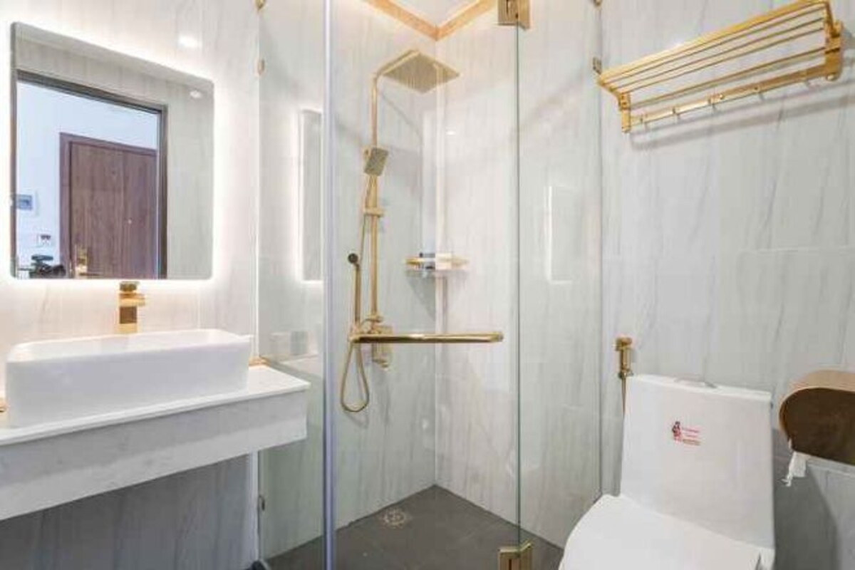 Un baño moderno con ducha envuelta en vidrio, un lavamanos blanco y un inodoro.