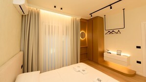 A modern bedroom with a bed, a vanity with a mirror, and a wardrobe. - E&K 01-02 Apartment (Vlorë)