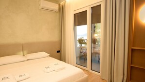 A hotel room with a bed, a sliding glass door to a balcony, and an air conditioning unit on the wall. - E&K 01-02 Apartment (Vlorë)