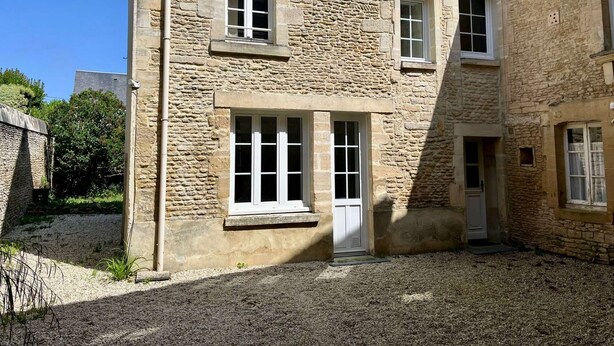 Un bâtiment en pierre avec une allée gravillonnée et une porte.