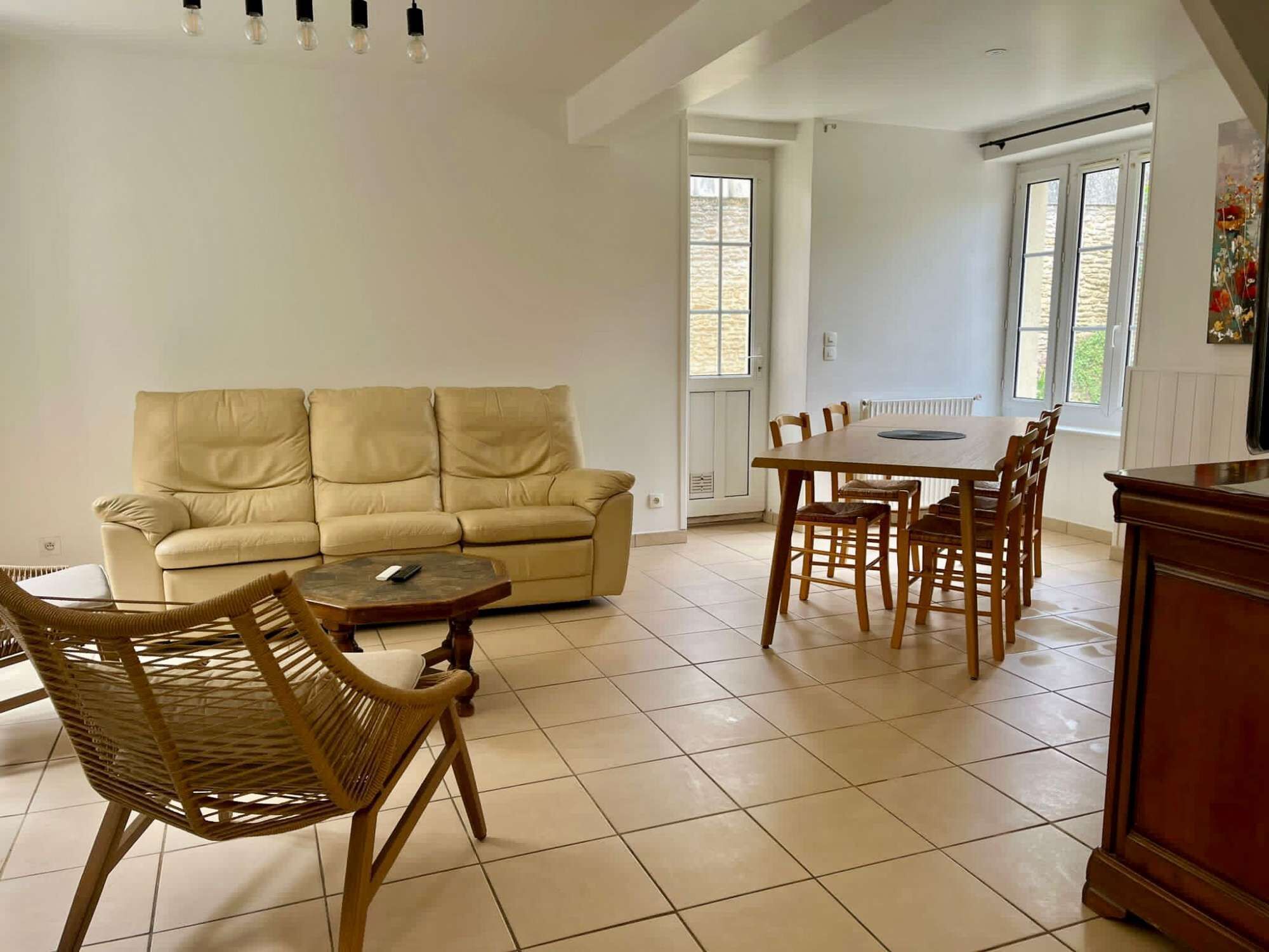 A living room with a beige sofa, a coffee table, and a dining table with chairs.
