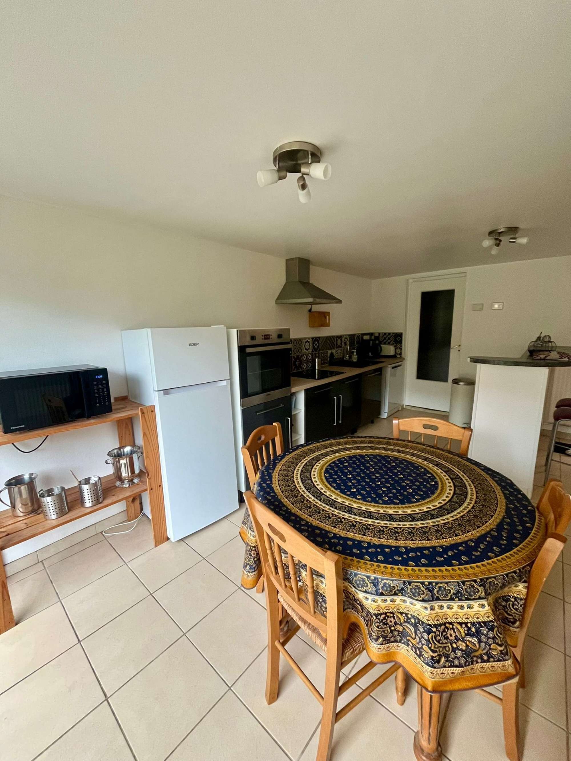 A compact kitchen with a dining area, including a microwave, refrigerator, stove, and a round table with chairs.