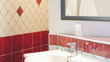 A bathroom with a white sink, red and white tiled walls, and a mirror above the sink.