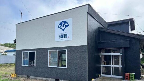 A modern building with a sign that includes a logo and Japanese characters.