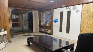A room with a large wooden table, a black leather chair, a glass door, and a whiteboard with various writings and drawings.