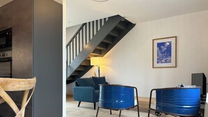 A modern living room with a staircase, a sofa, a wooden chair, and blue barrels. - Typical Breton house "Ty Breizh" Beg Meil Fouesnant plage des oiseaux (Fouesnant)