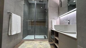 Ein modernes Badezimmer mit einer Duschkabine, einem großzügigen Waschbecken und einem Spiegel.