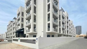Un immeuble résidentiel moderne à plusieurs étages, doté de balcons et de grandes fenêtres.